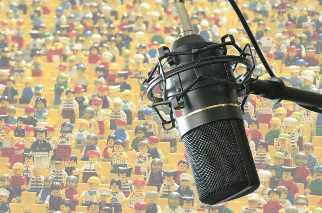 An audio microphone superimposed on a crowd image of many lego people figures... maybe 294 of them?